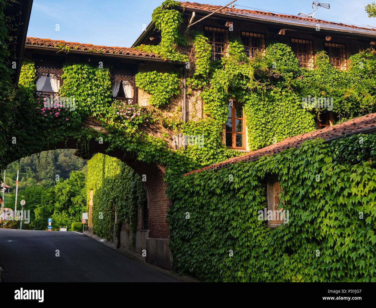 Biella, Italie, 10 juin 2018 - maison ancienne, les murs couverts de lierre et d'arche reliant la deuxième partie de la chambre avec road ci-dessous, Italie Banque D'Images