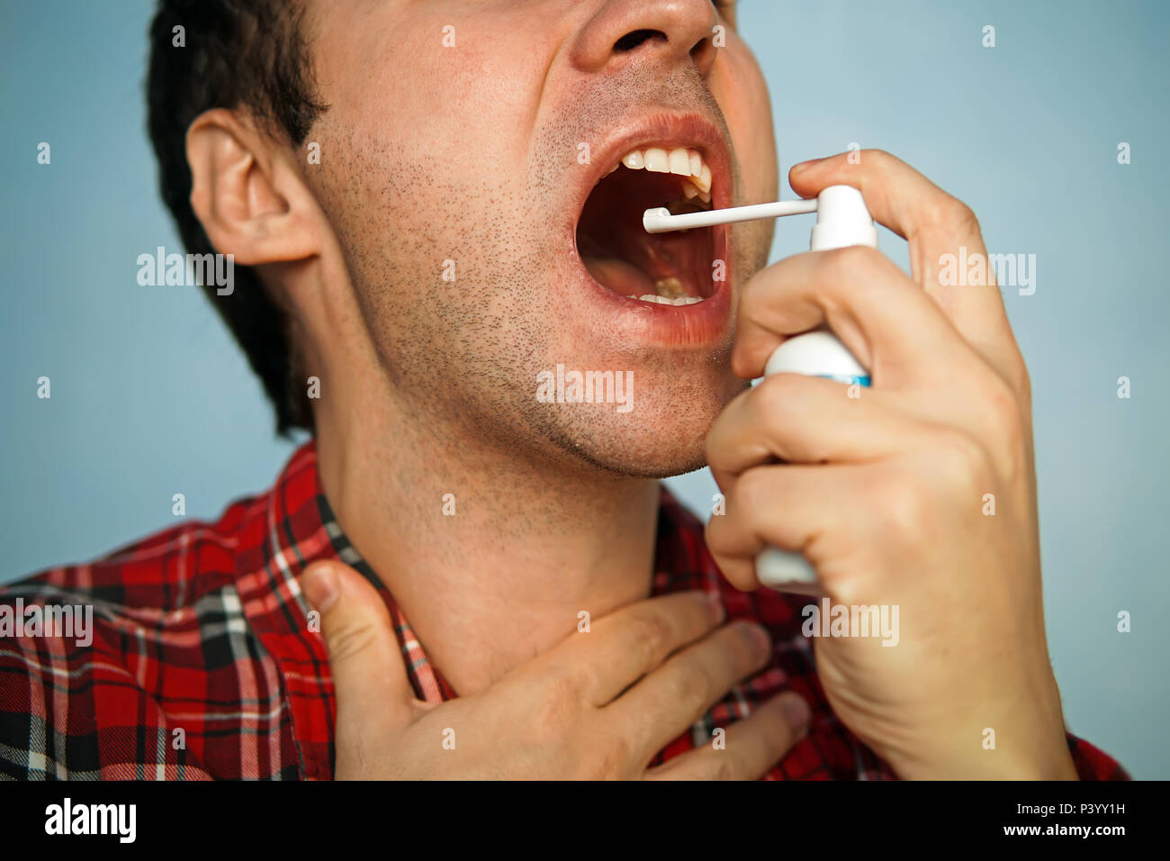 Allergies et maux de gorge concept. Jeune homme malade à l'aide de pulvérisation. maux de gorge. Démangeaisons dans la gorge. Maladie catarrhale de traitement. Haleine fraîche menthol. Banque D'Images