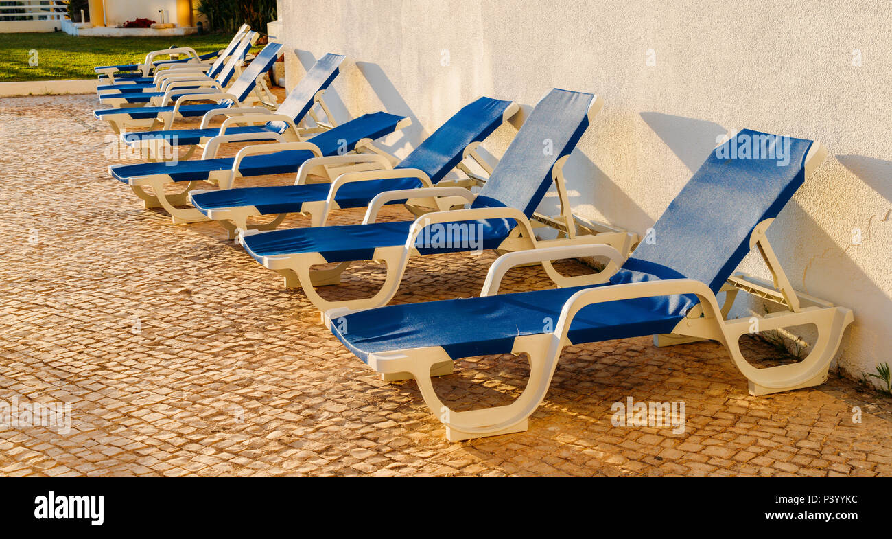 Des chaises en plastique bleu sur les pavés, avec un soleil d'été Banque D'Images
