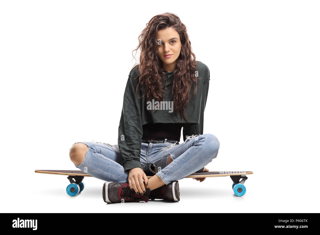 Skater girl assis sur un longboard et regardant la caméra isolé sur fond blanc Banque D'Images