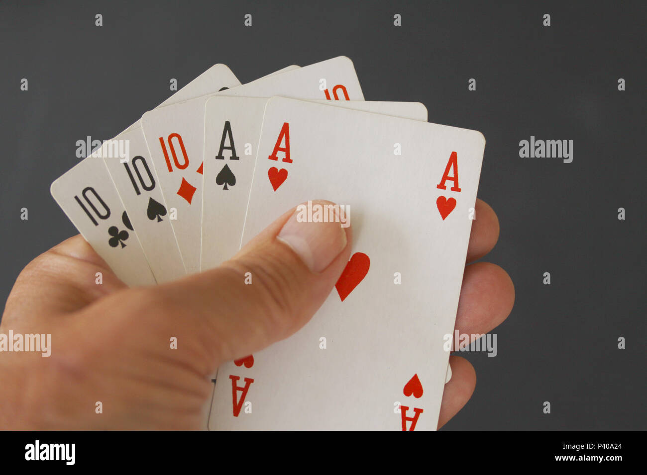 Main de poker avec trois cartes de 10 et deux as - close up sur fond noir Banque D'Images
