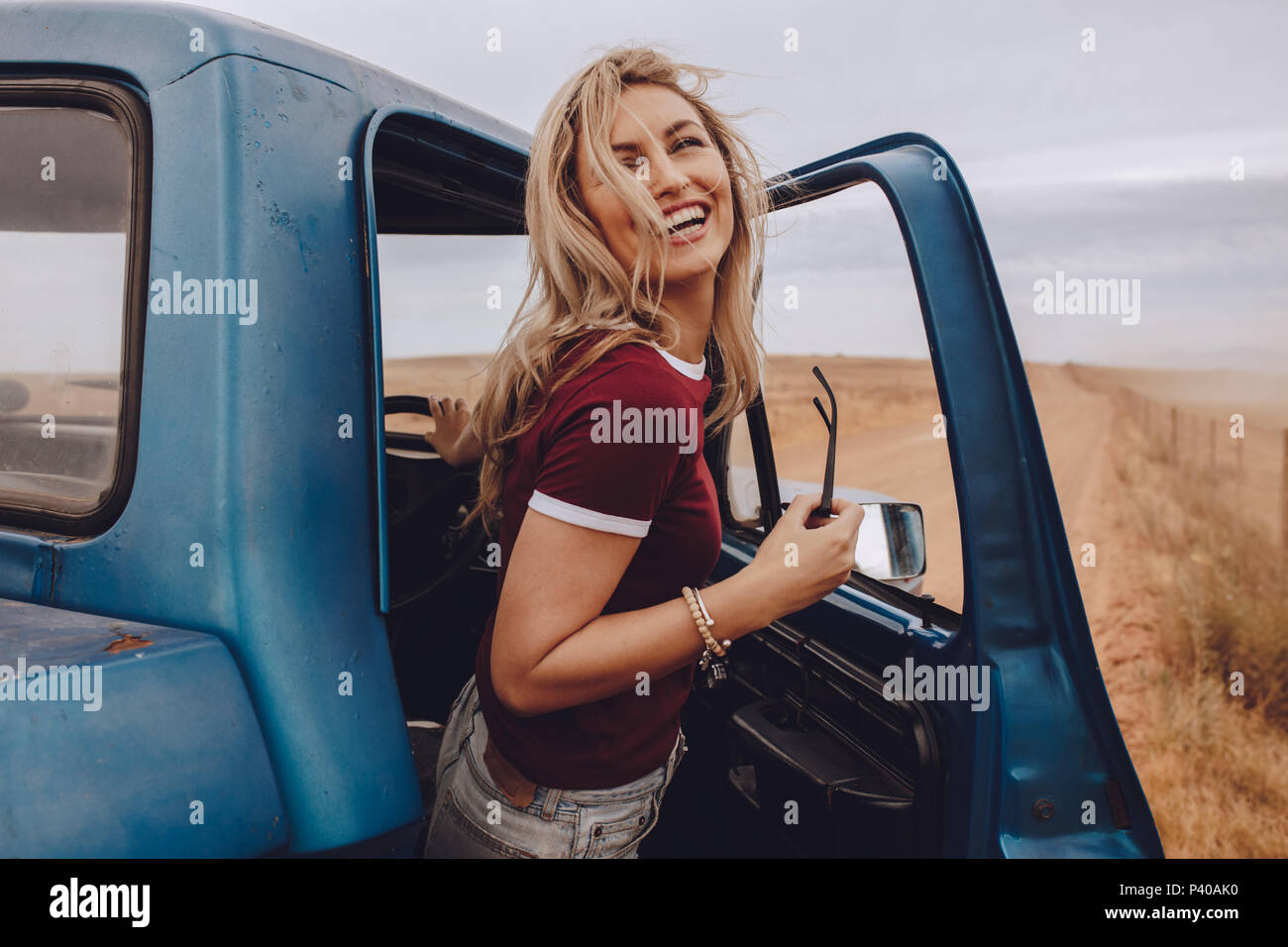 Portrait of young woman standing by sa voiture et rire. Pause de la femme qui voyage. Banque D'Images