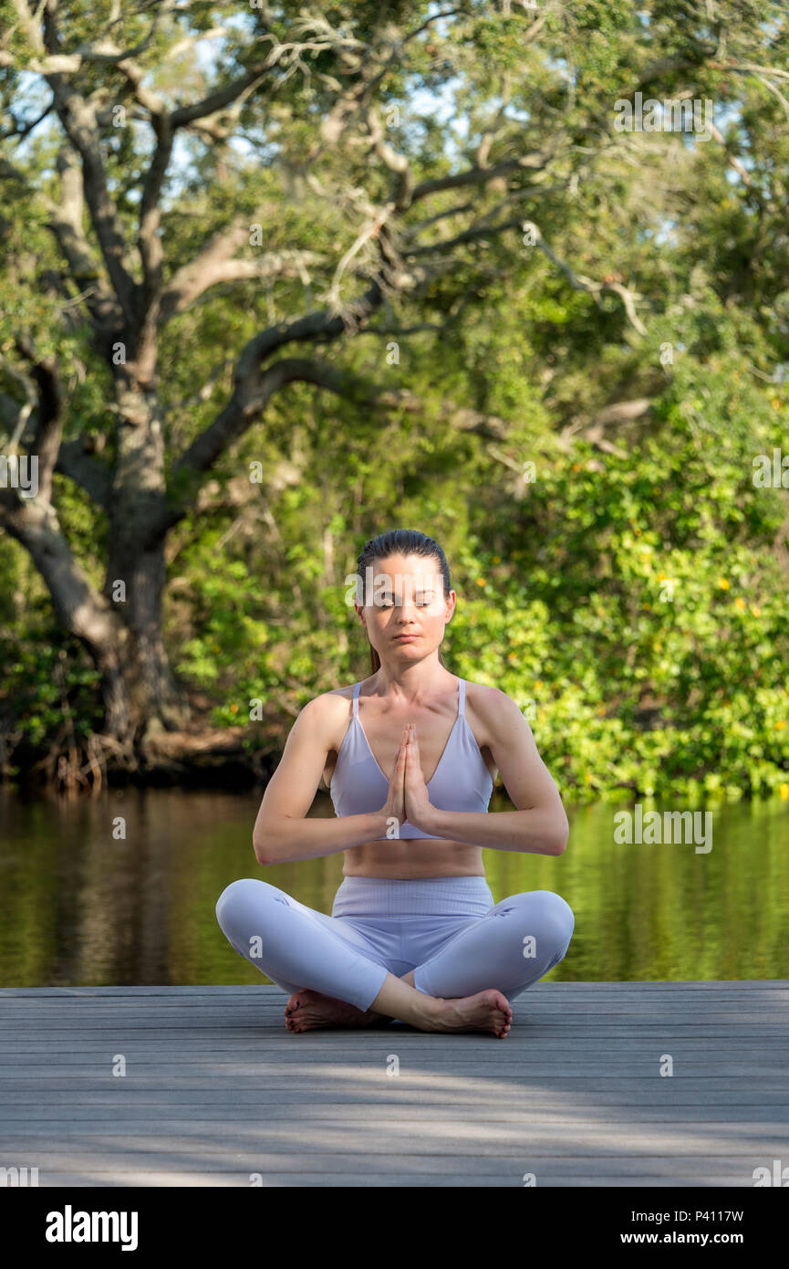 Femme assise sur le pont de l'eau par la pratique du yoga et méditation Banque D'Images
