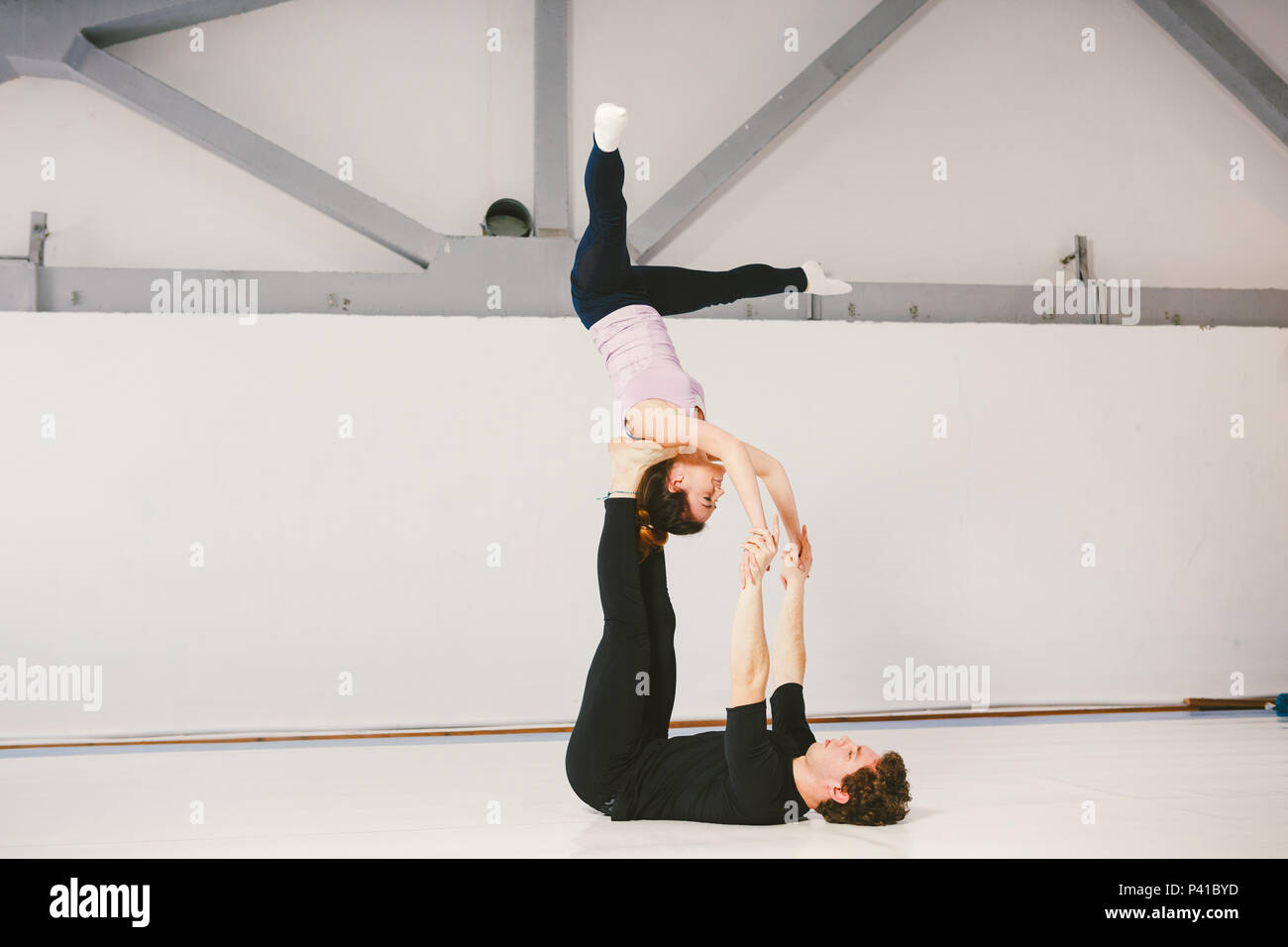 Un jeune homme de race blanche et de sexe féminin couple practicing yoga  acrobatique dans un livre blanc sur les tapis de gym. Ils sont dans la  posture de l'étoile Photo Stock -