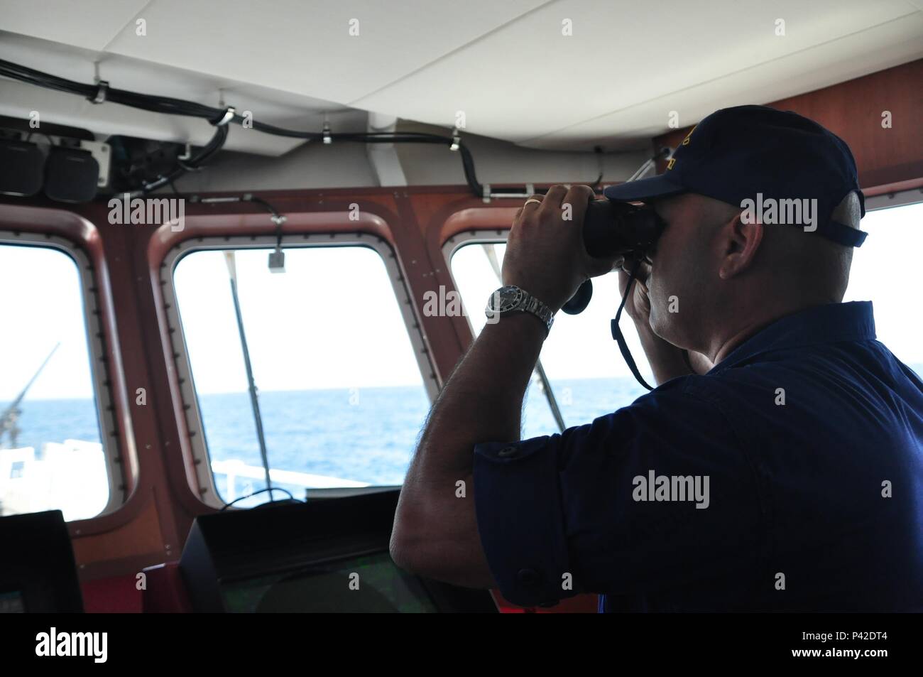 Le premier maître de Francisco Hernandez, un maître de manœuvre à bord du garde-côte de Heriberto Hernandez, regarde à travers des jumelles pendant un exercice de tir conjoint dans la mer des Caraïbes, le 9 juin 2016 au cours de Tradewinds 2016. Tradewinds 2016 est un exercice combiné mixte menée de concert avec les pays partenaires pour améliorer la capacité collective des forces de défense et constabularies pour lutter contre la criminalité transnationale organisée et d'effectuer des opérations de secours en cas de catastrophe/humanitaire. U.S. Coast Guard photo de Maître de 1re classe Melissa Leake Banque D'Images