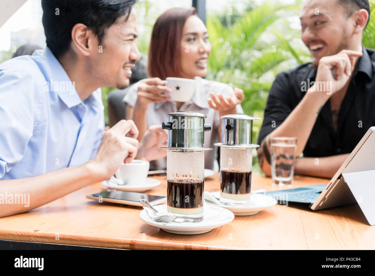 Café vietnamien servi sur la table des trois amis à l'extérieur Banque D'Images