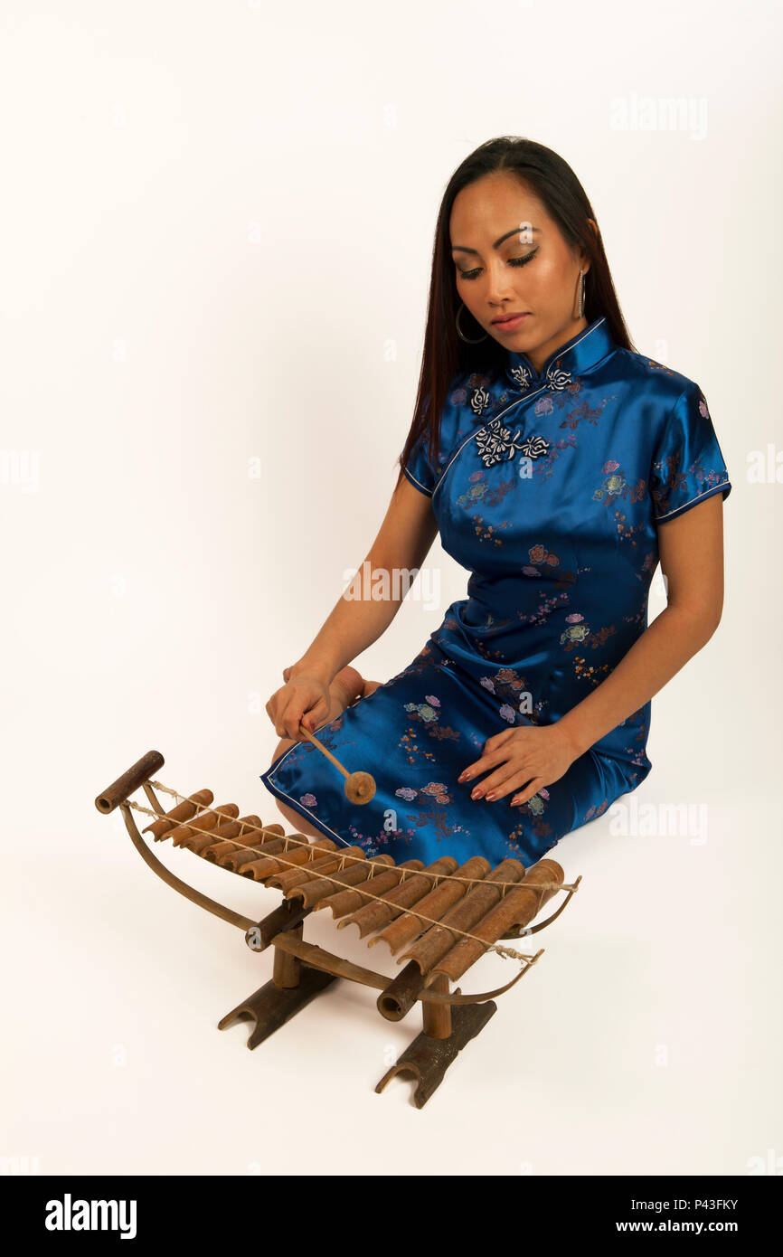 Femme chinoise jouant un xylophone de bambou avec un hérisson en bois. Instrument traditionnel. Banque D'Images