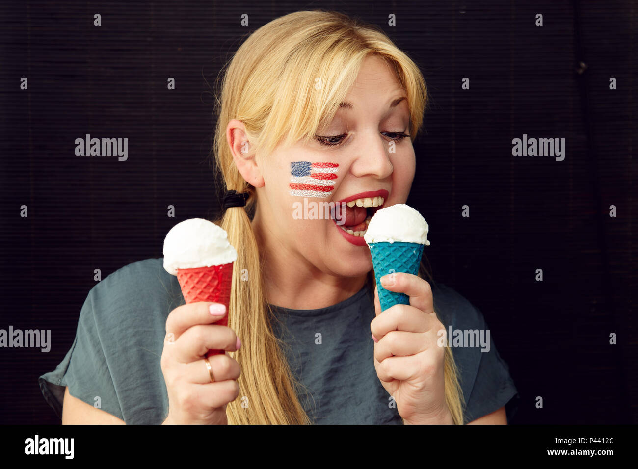 Fille avec le drapeau américain sur son visage la consommation de crème glacée. US Independence Day. Banque D'Images