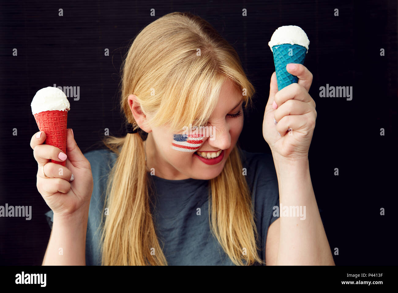 Fille avec le drapeau américain sur son visage la consommation de crème glacée. US Independence Day. Banque D'Images