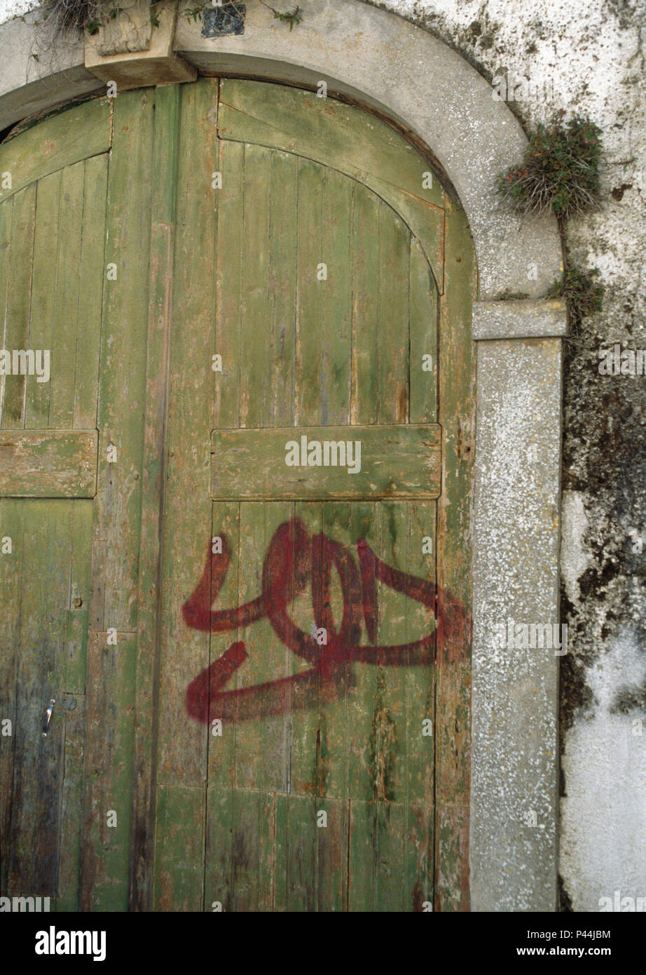 Des graffitis sur des doubles portes en bois sur une maison portugaise délabrée Banque D'Images