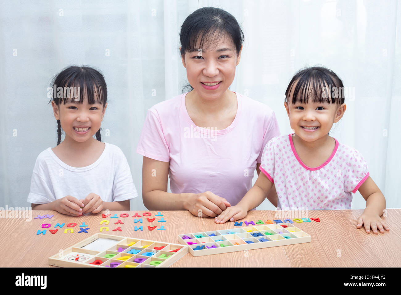 La famille chinoise asiatique jouant avec l'alphabet en bois coloré à la maison des jouets Banque D'Images