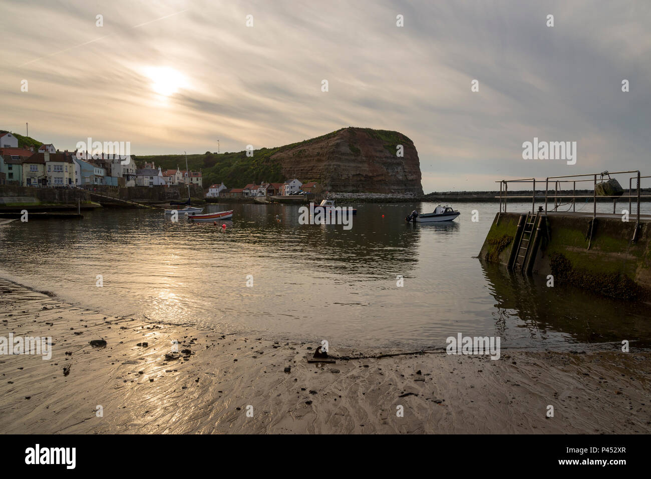 Belle soirée de mai dans le village pittoresque de Staithes, Yorkshire du Nord. Le coucher de soleil dans un ciel de nuages au-dessus du port. Banque D'Images