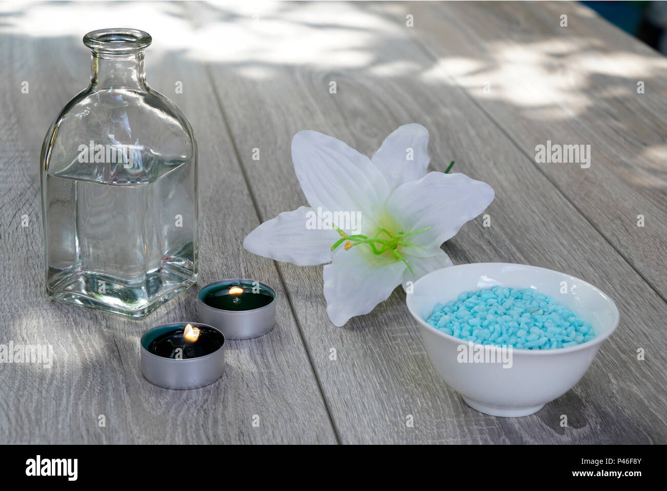 Une bouteille, de fleurs blanches, sels de bain et de bougies, de détente en plein air sur une table en bois... Banque D'Images