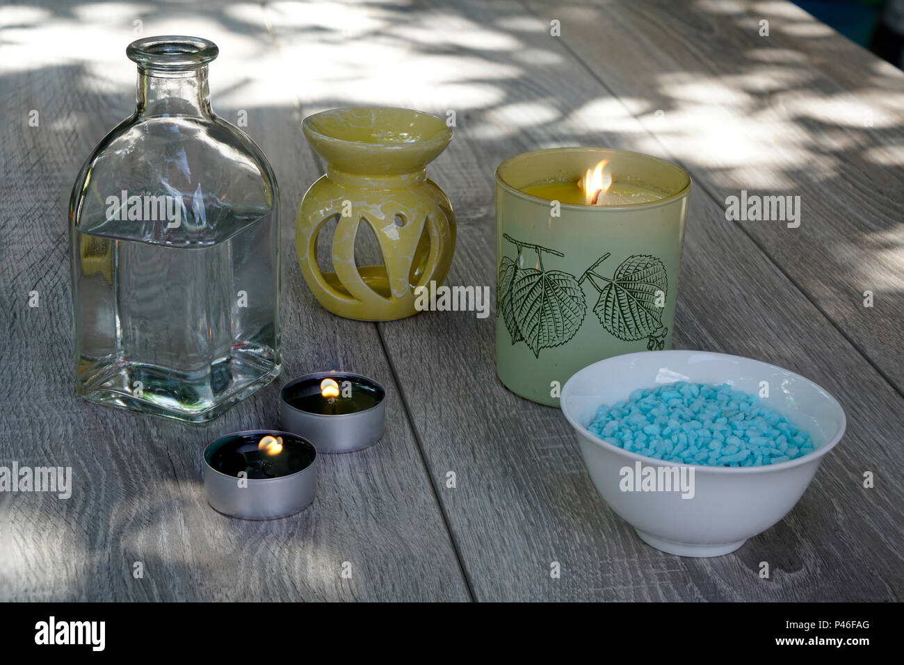 Une bouteille, de fleurs blanches, sels de bain et de bougies, de détente en plein air sur une table en bois... Banque D'Images