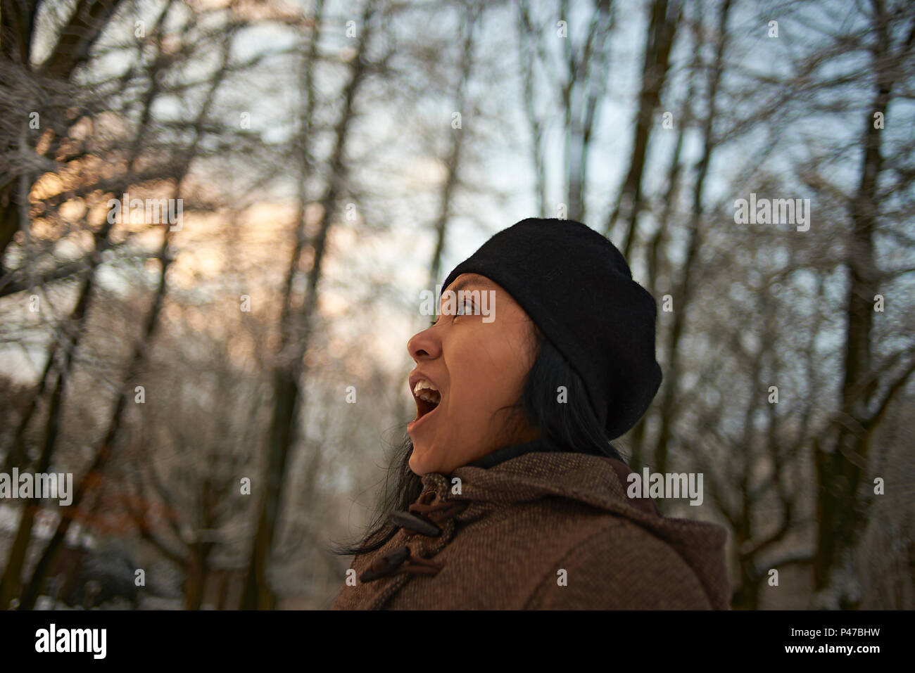 Vue de profil d'une femme asiatique en vêtements d'hiver dans une forêt à l'aube des premières neiges en hiver sunshine Banque D'Images