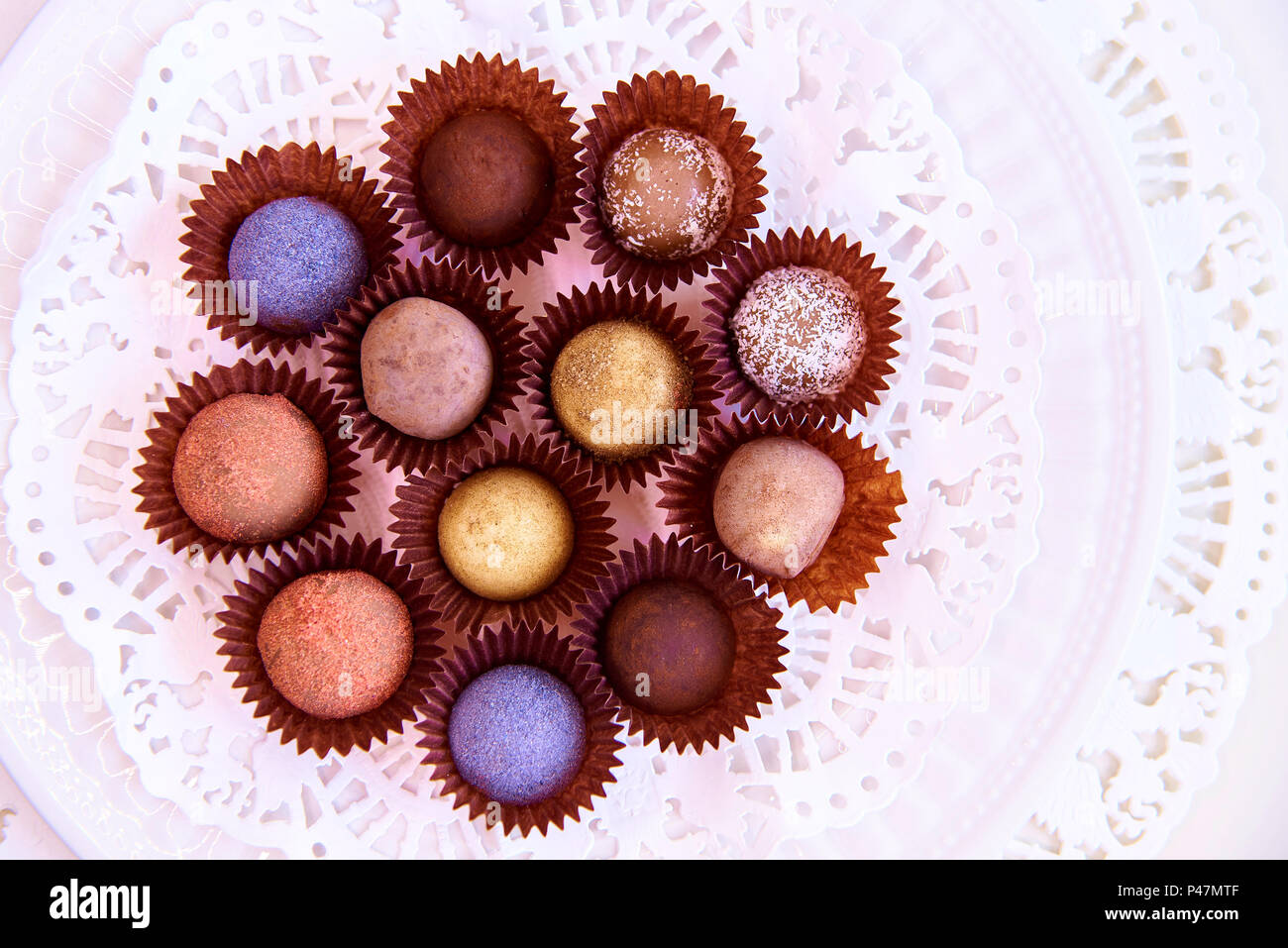 Un ensemble de bonbons truffe de couleur sur une plaque blanche avec de la dentelle. Banque D'Images