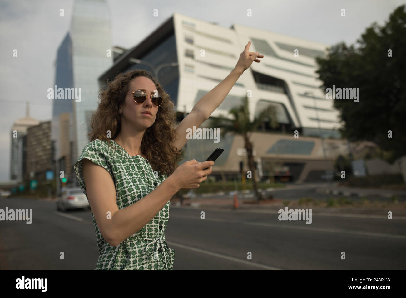 Woman hailing pour rouler avec un téléphone mobile dans la main Banque D'Images