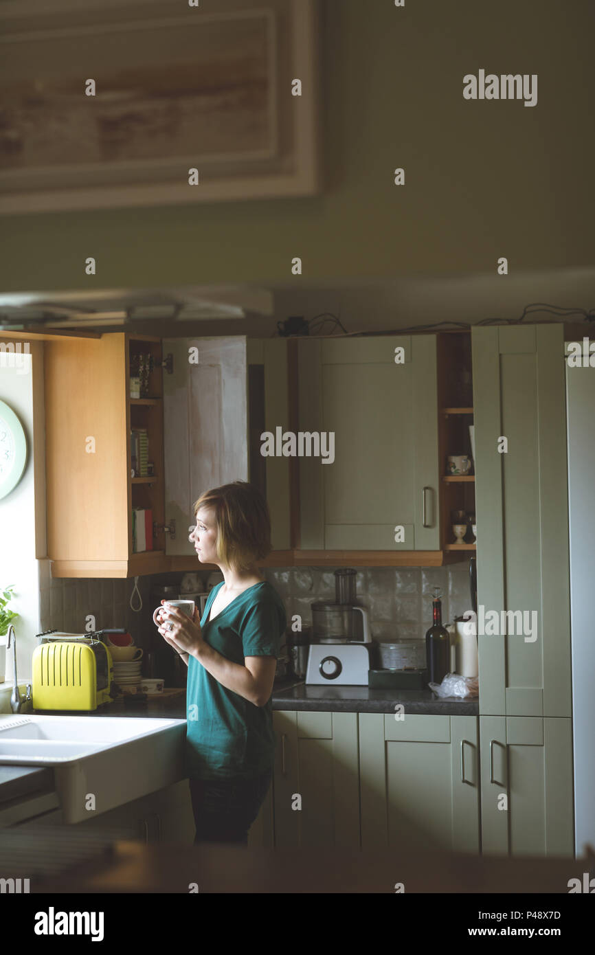 Woman having coffee in kitchen Banque D'Images