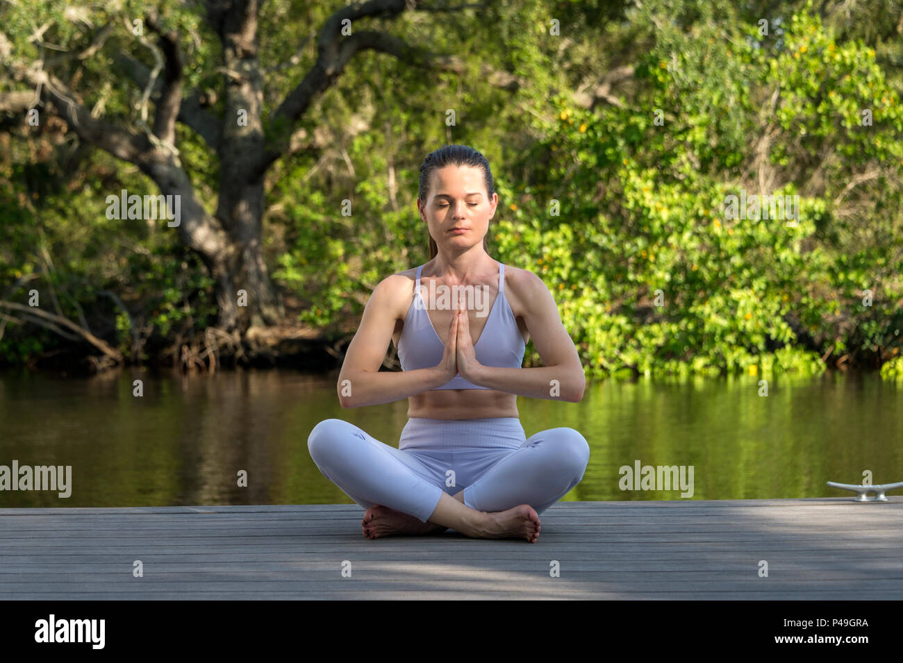 Femme assise sur une plate-forme de l'eau par la pratique du yoga et la méditation Banque D'Images
