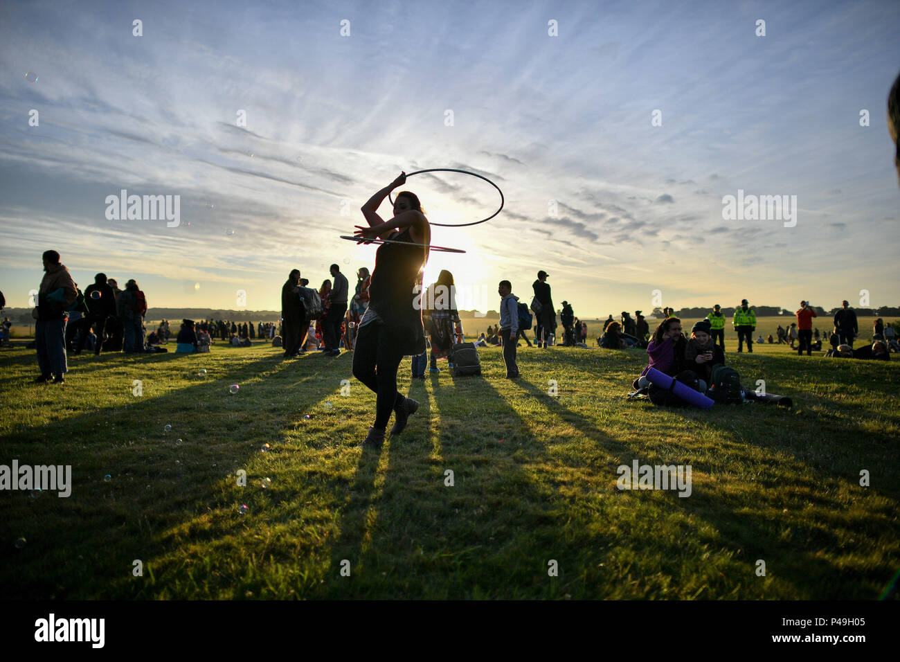 Une femme tournoie un cerceau comme le soleil se lève à Stonehenge où les gens ont célébré l'aube du jour le plus long dans le Royaume-Uni. Banque D'Images