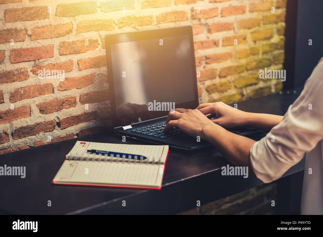 Les femmes qui travaillent main tapant portable avec carnet et un stylo dans le café pendant la nuit. Banque D'Images