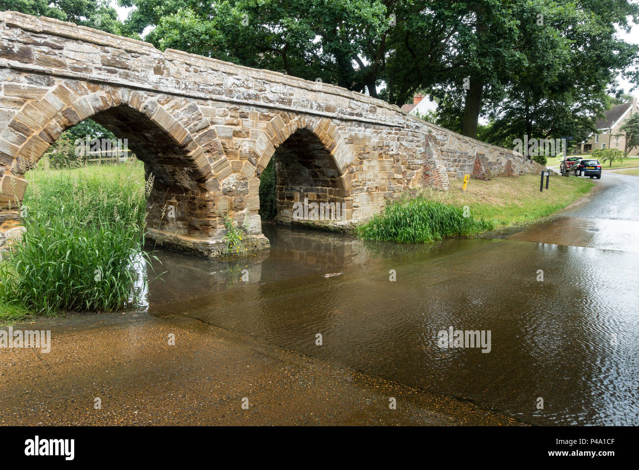 Une passerelle en pierre sur une Ford dans un village typiquement anglais en été. Sutton, Bedfordshire Banque D'Images