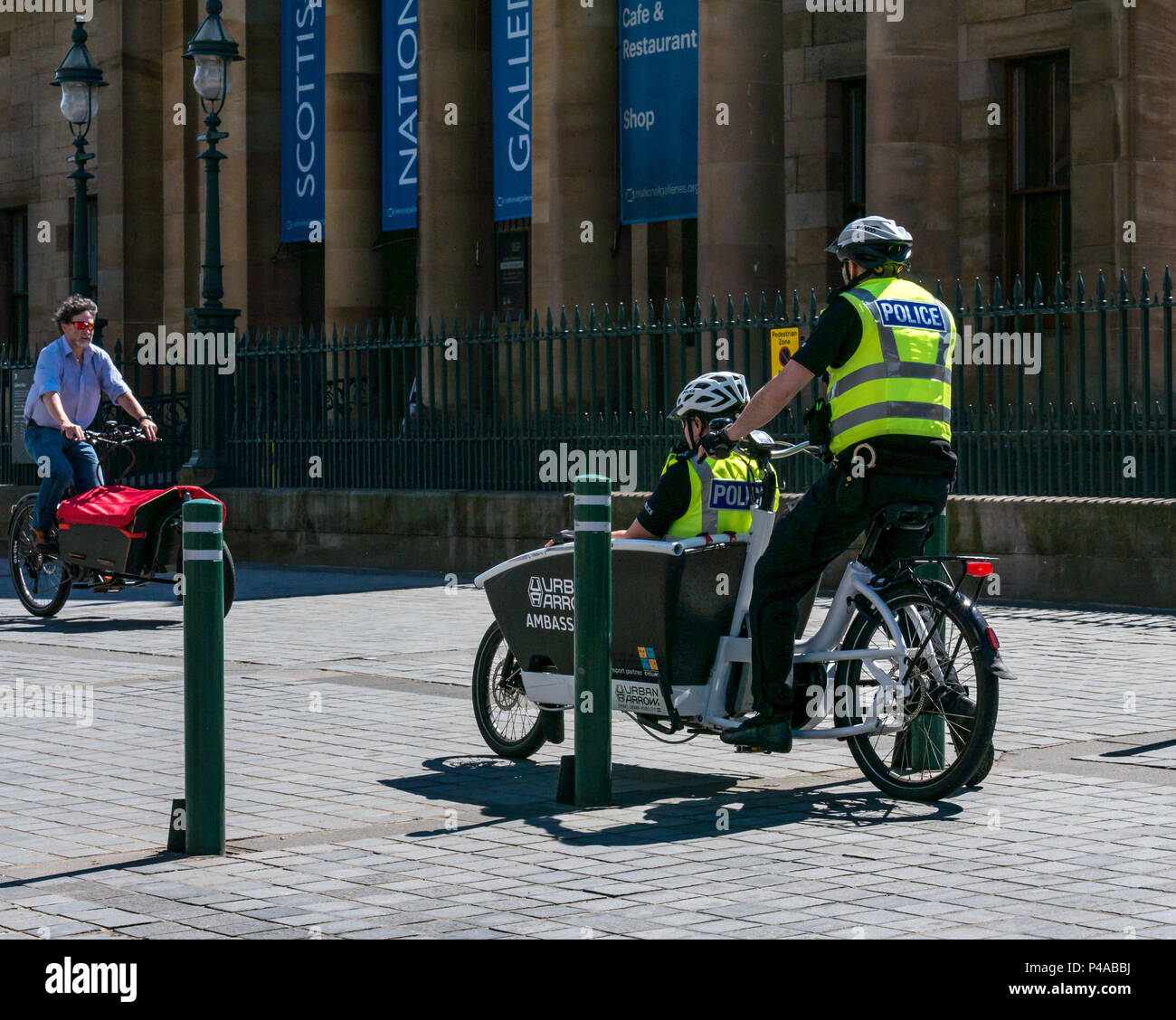 Édimbourg, Écosse, Royaume-Uni, 21st juin 2018. La Mound de la National Gallery a été fermée ce matin aux véhicules pour permettre aux gens d'essayer les vélos électriques dans le cadre d'un événement organisé par Electron Wheels. Deux policiers essaient un vélo électrique Urban Arrow Banque D'Images