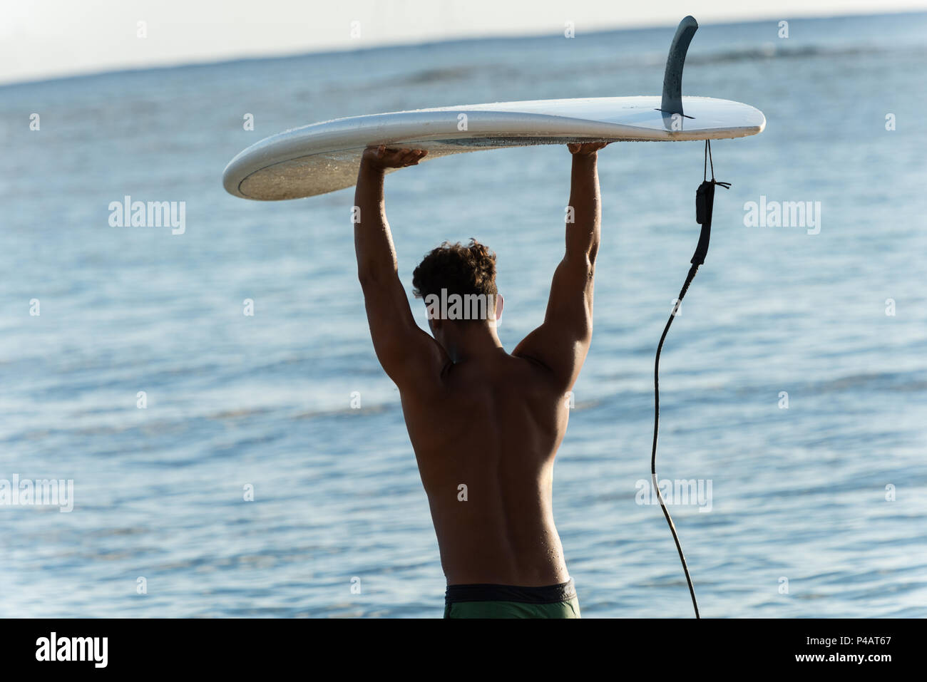 Homme marchant avec planche de surf à la plage Banque D'Images