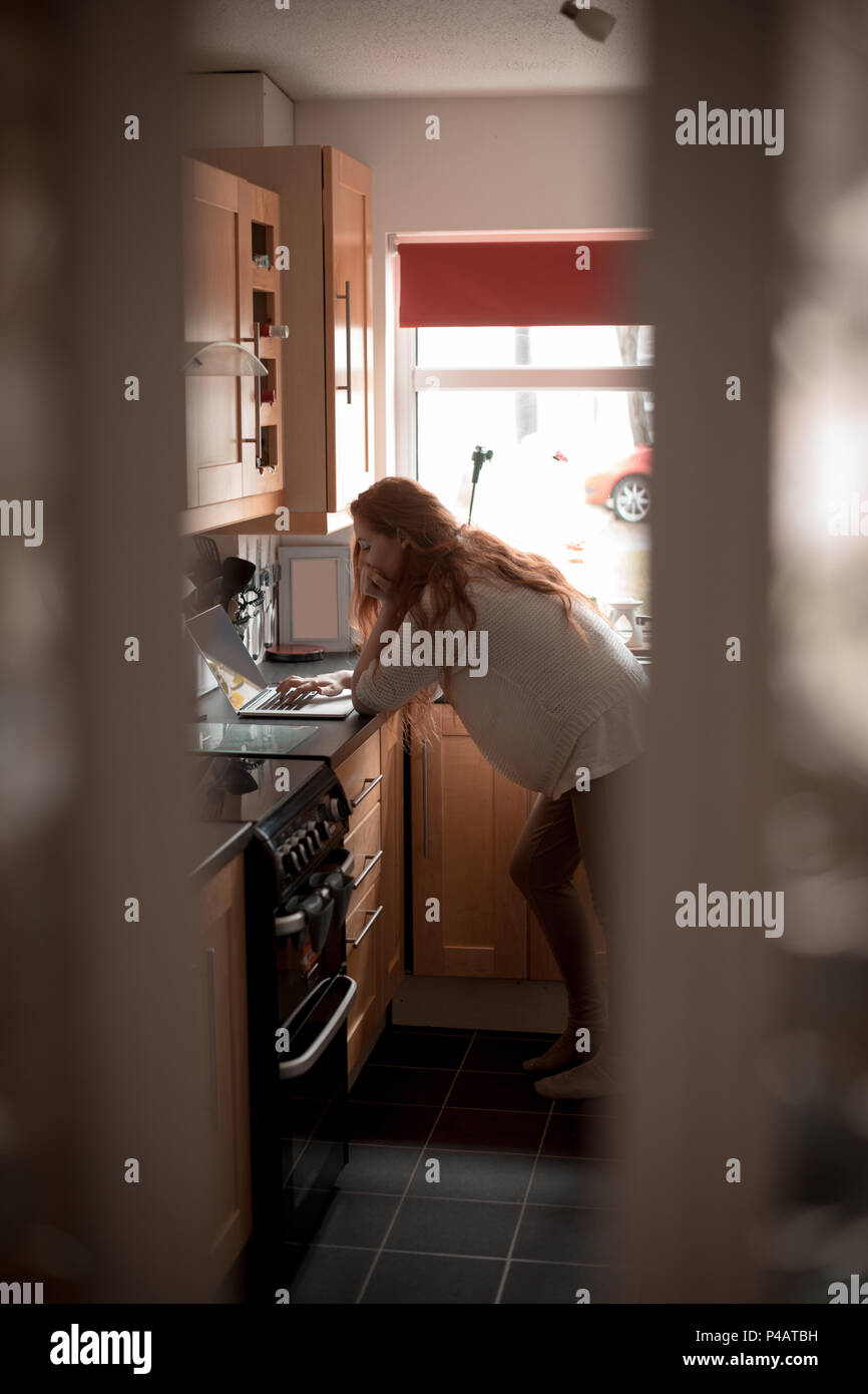 Woman using laptop in kitchen Banque D'Images