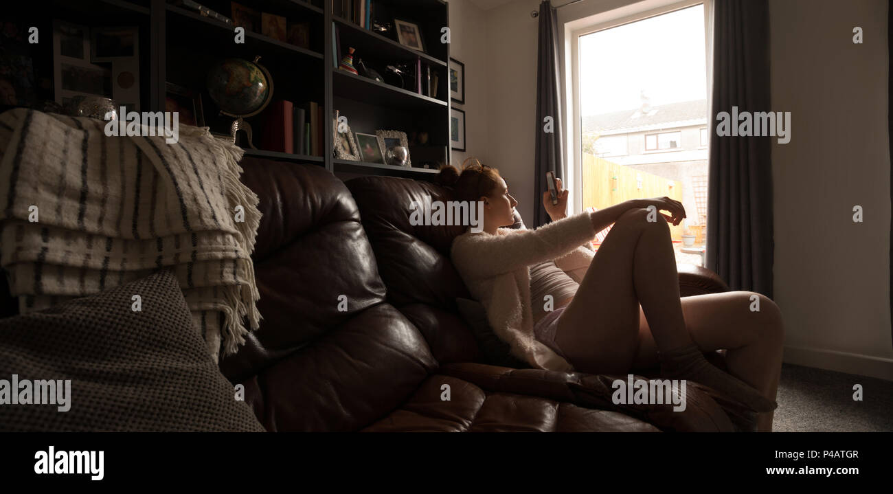 Woman relaxing in living room à la maison Banque D'Images