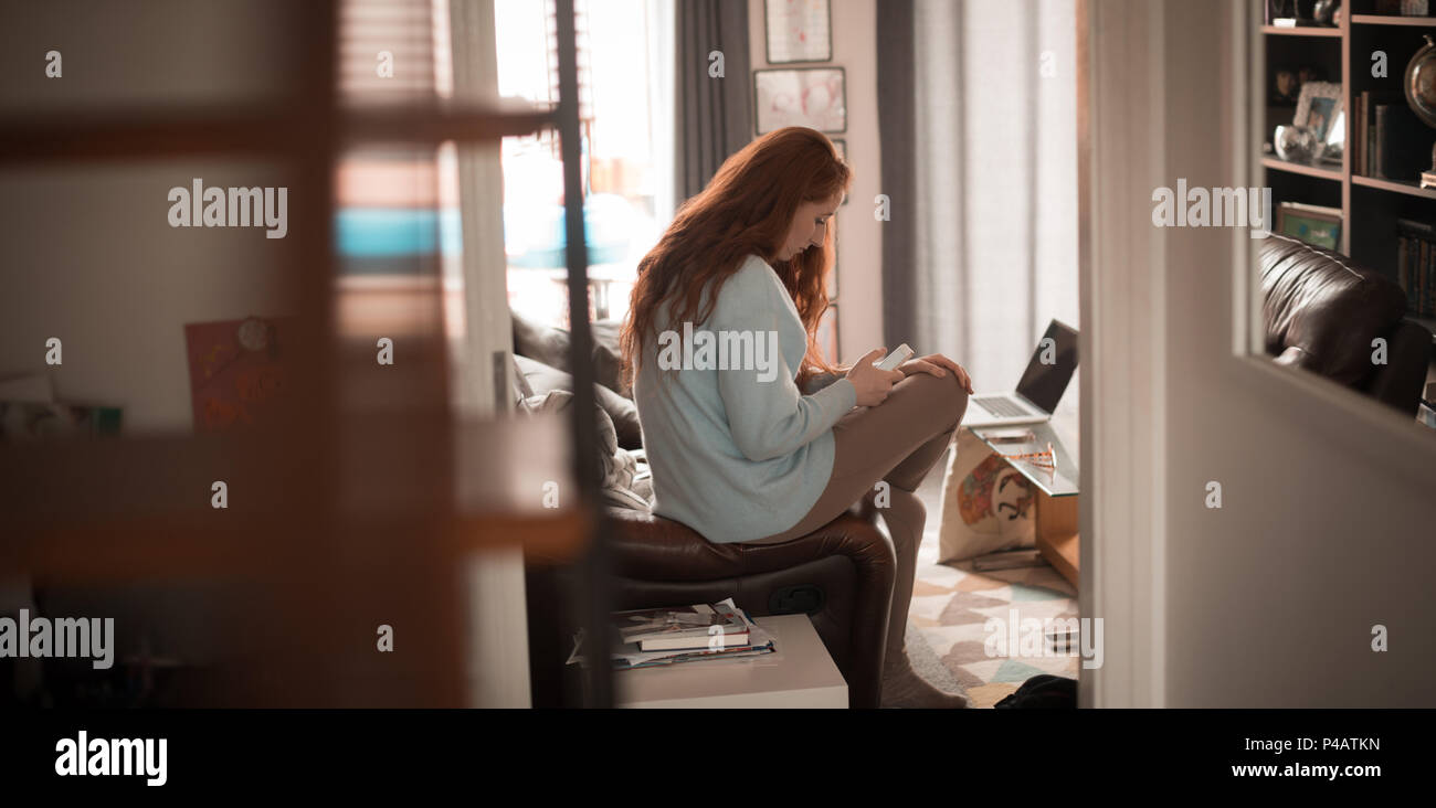 Woman using mobile phone at home Banque D'Images