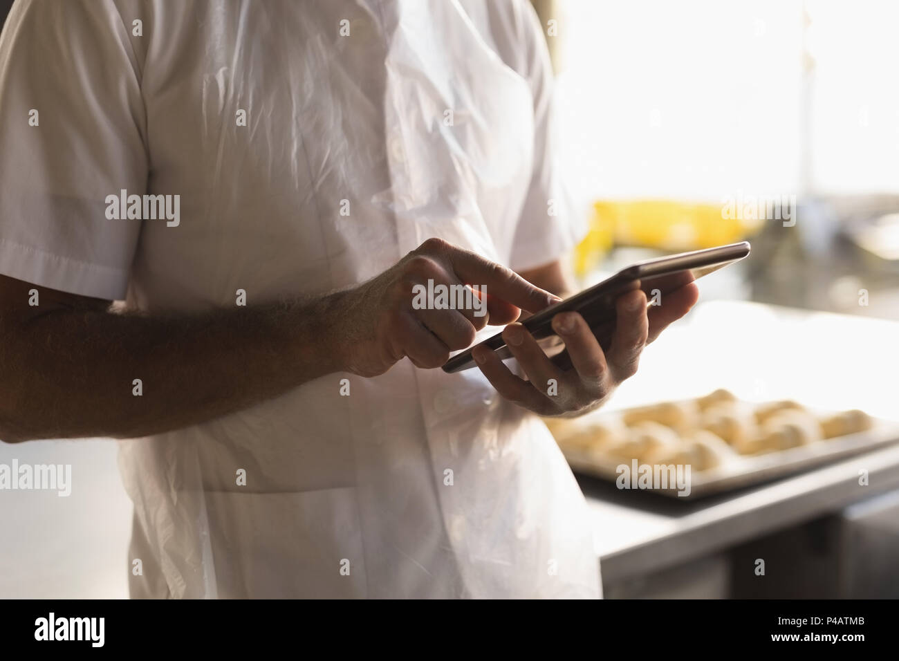 Male baker using digital tablet in bakery shop Banque D'Images