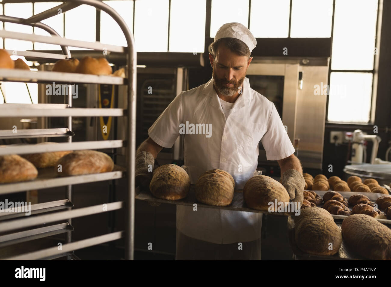 Male baker holding a tray de pains Banque D'Images