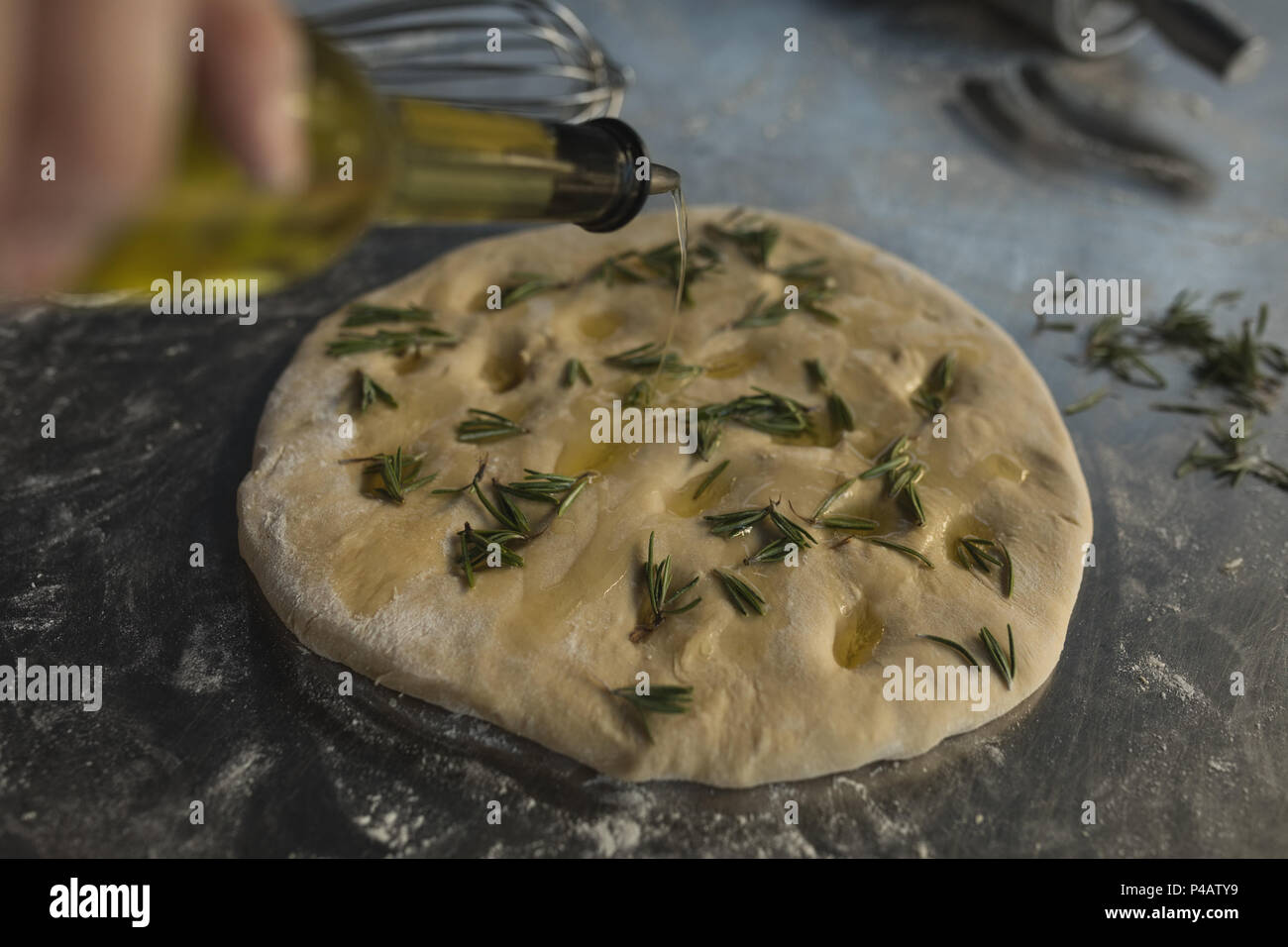 Male baker versez de l'huile sur une pâte Banque D'Images