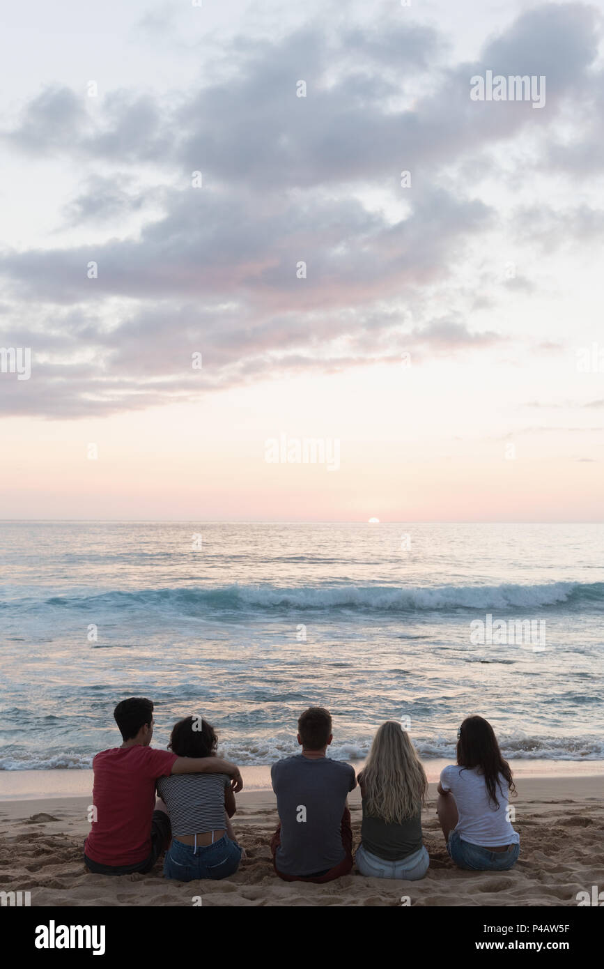 Groupe d'amis assis ensemble dans la plage Banque D'Images