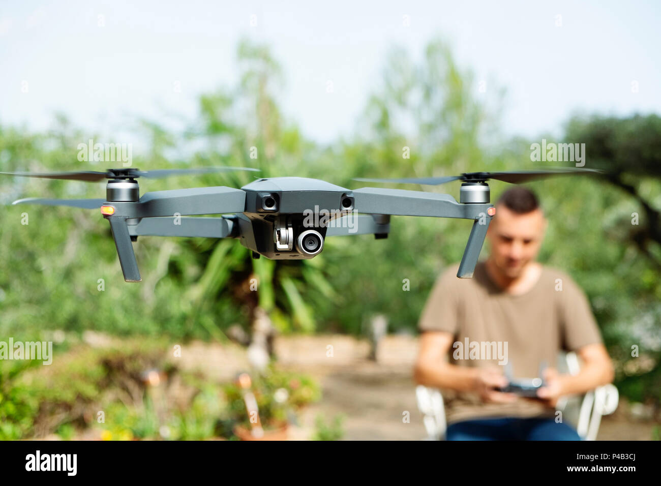 Libre d'un homme de race blanche, d'un drone d'exploitation contrôlé à distance avec un smartphone, dans un paysage naturel Banque D'Images