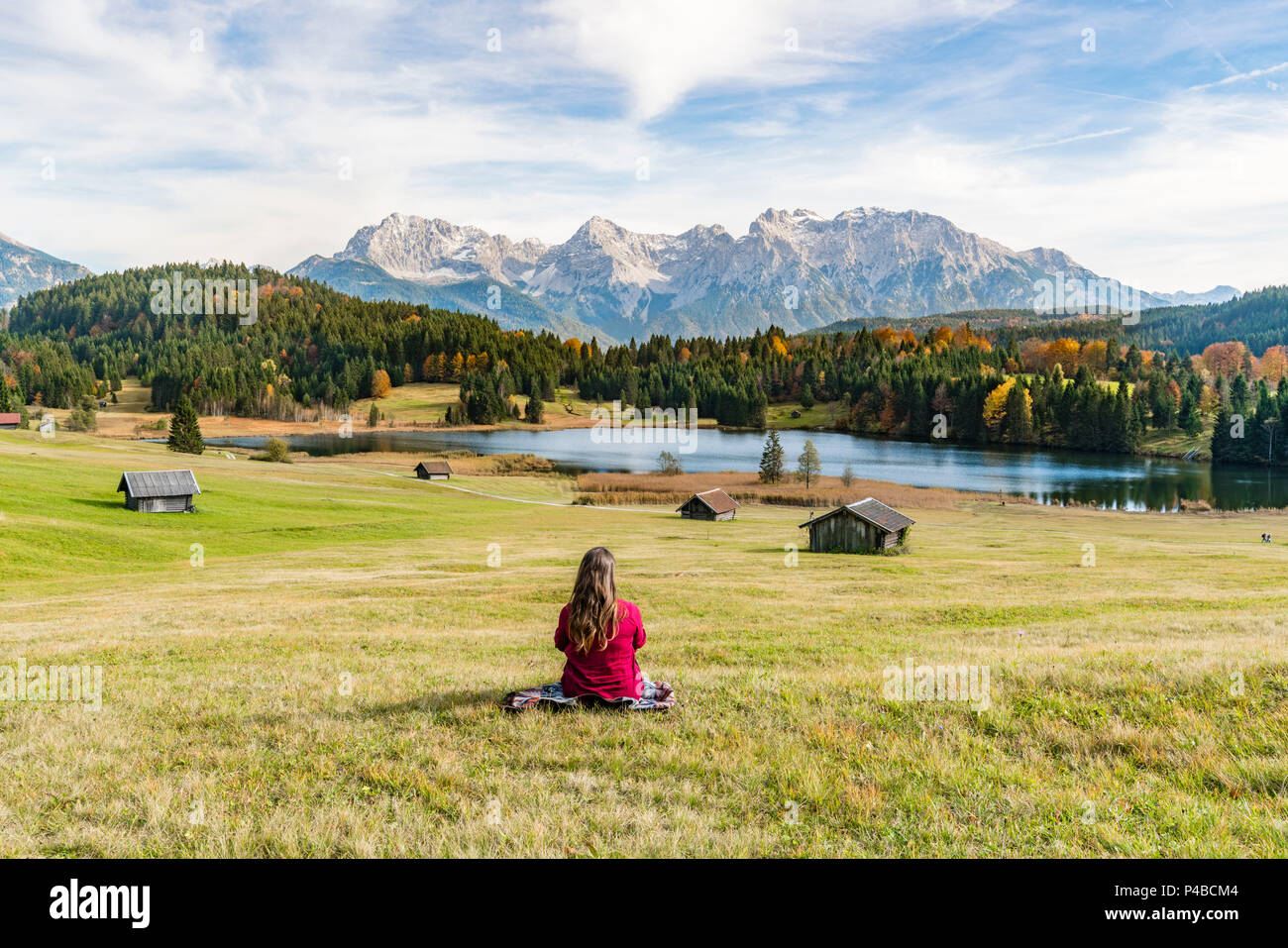 Femme assise et regardant Gerold lac et montagnes des Alpes. Krün, Upper Bavaria, Bavaria, Germany. Banque D'Images