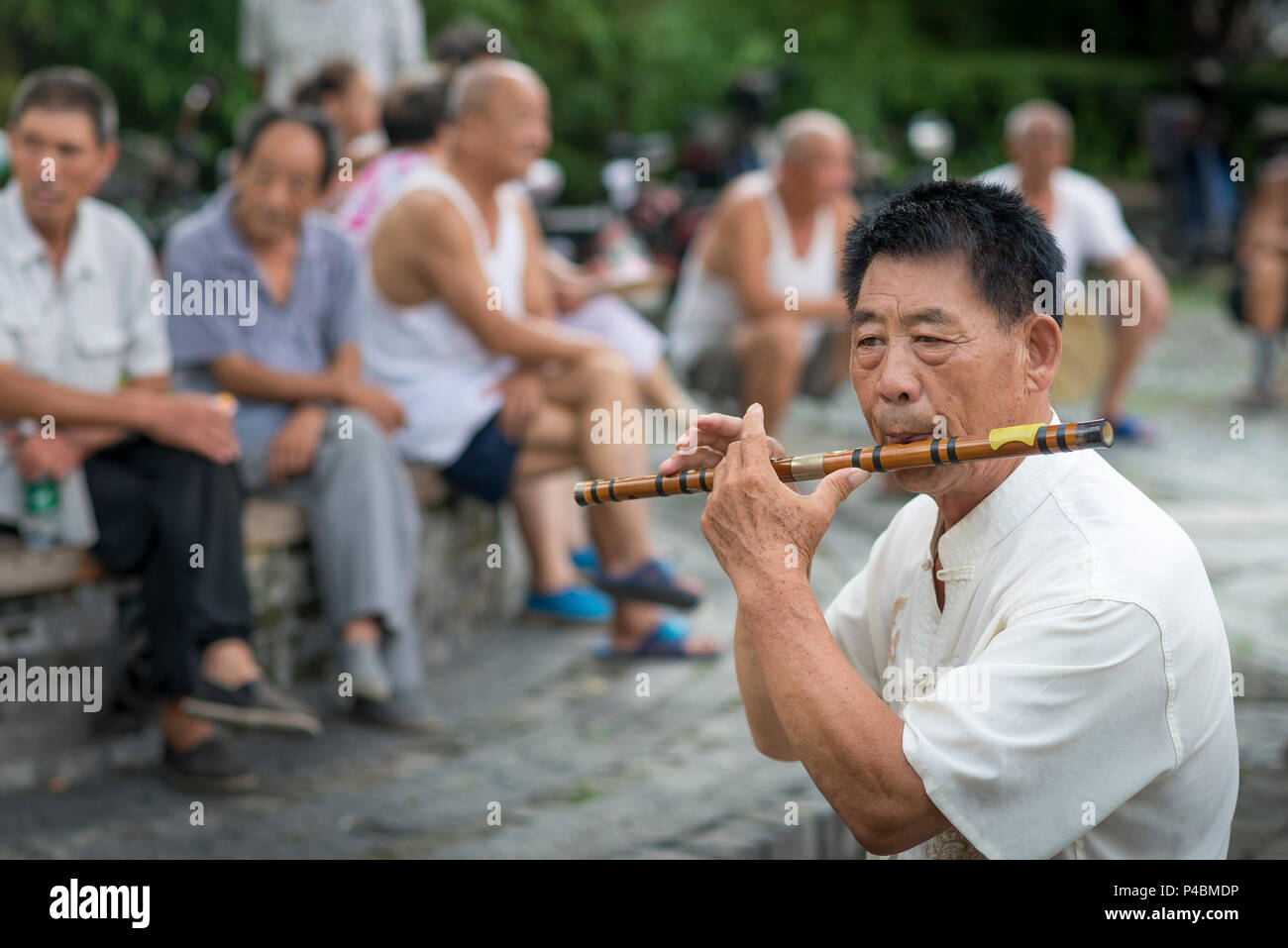 L'homme joue de la Flûte en bois traditionnel pour les adultes dans la rue de la ville et à la brunante, Ville de Nanyang, Qingdao, Shandong Province, China Banque D'Images