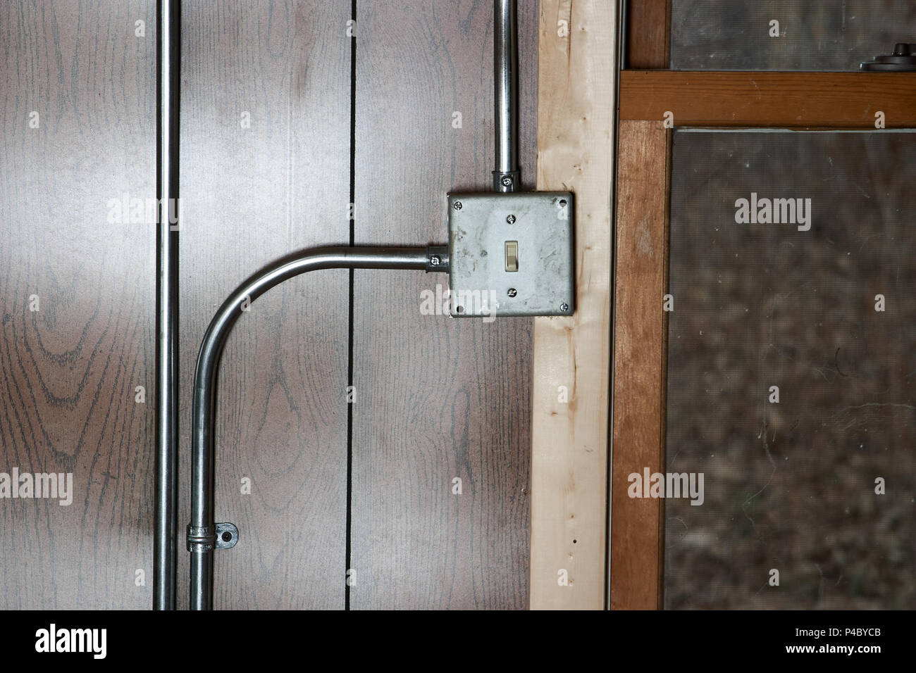 Old grunge metal monté en surface de l'interrupteur de l'électricité avec des tuyaux de conduite sur un mur lambrissé de bois Banque D'Images