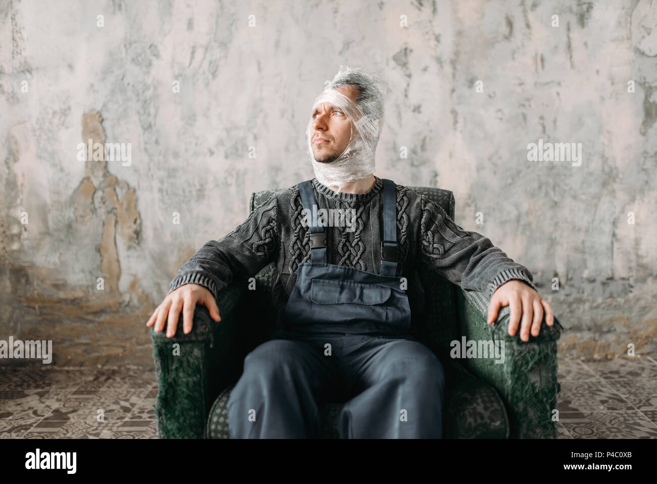 Autist avec film plastique sur la tête assis sur une chaise Banque D'Images