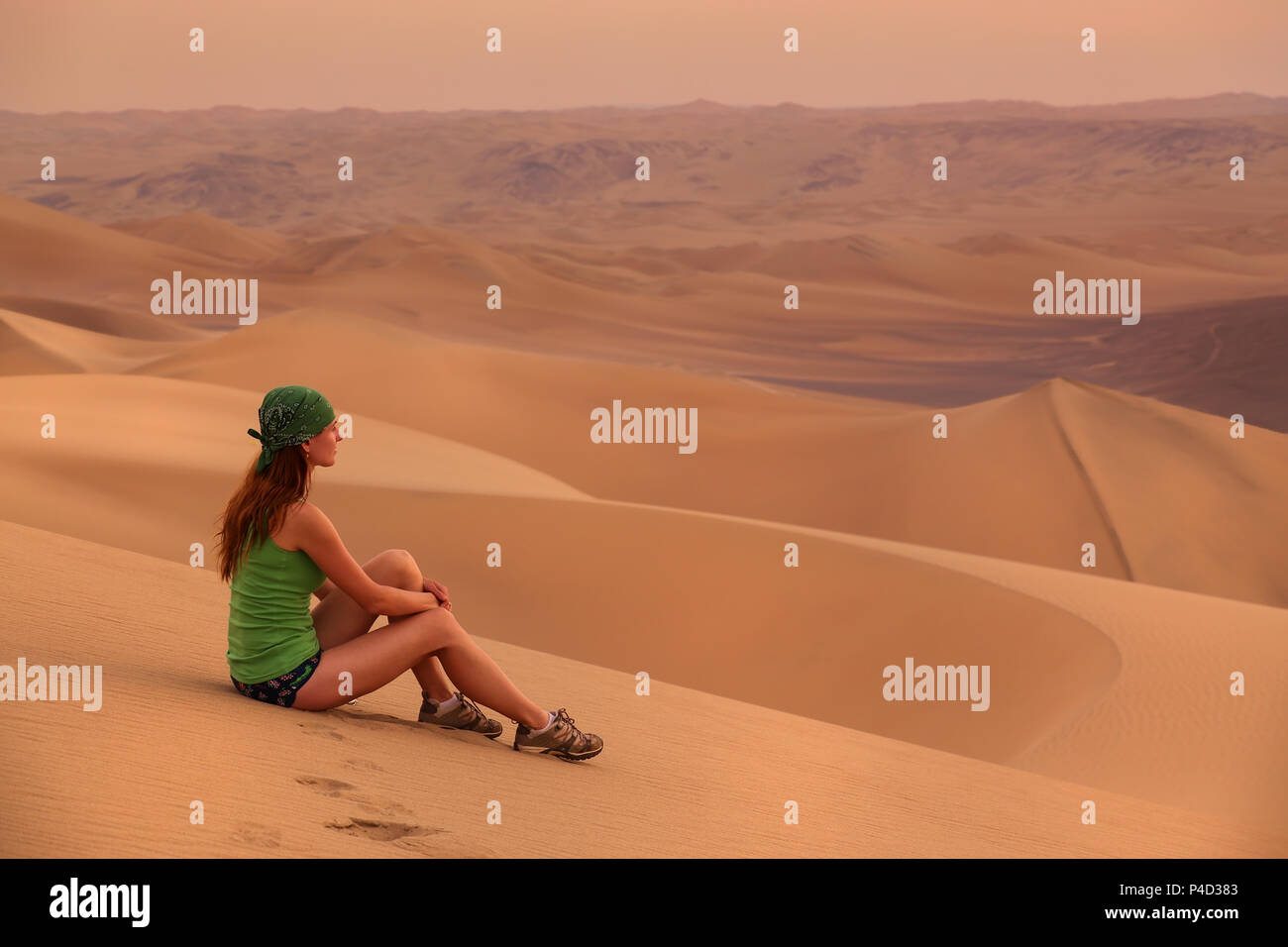 Jeune femme assise sur le sable dans un désert près de Ica Huacachina, région, le Pérou. Banque D'Images