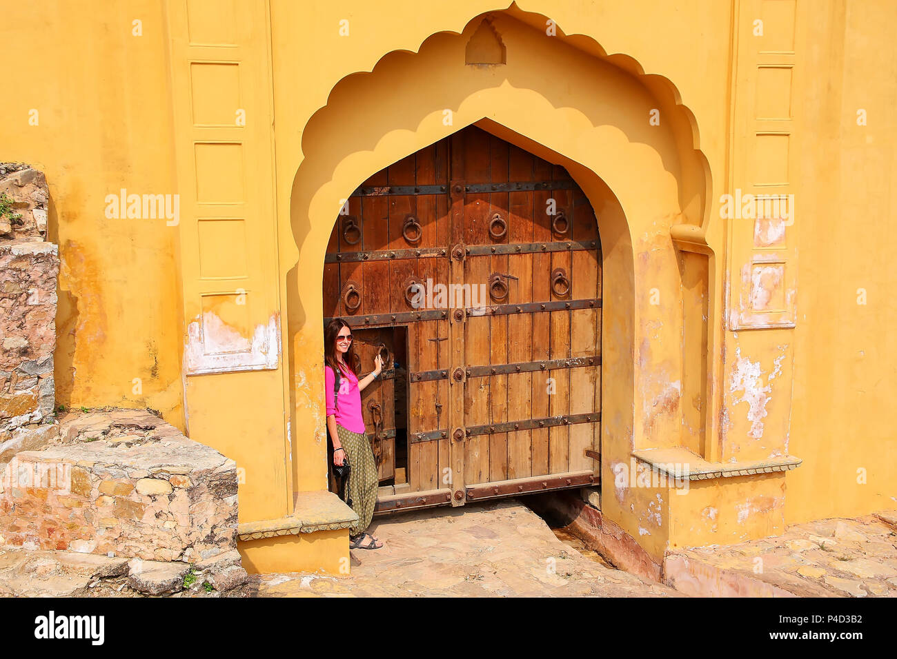 Jeune femme debout près de la porte à l'Amber Fort près de Jaipur, Rajasthan, Inde. Fort Amber est la principale attraction touristique dans la région de Jaipur. Banque D'Images