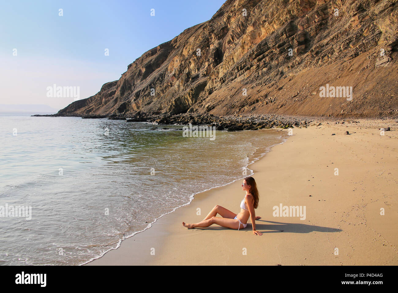 Young woman in bikini assis à La Mina Beach dans la réserve nationale de Paracas, au Pérou. Objectif principal de la réserve est de protéger l'écosystème marin et histo Banque D'Images