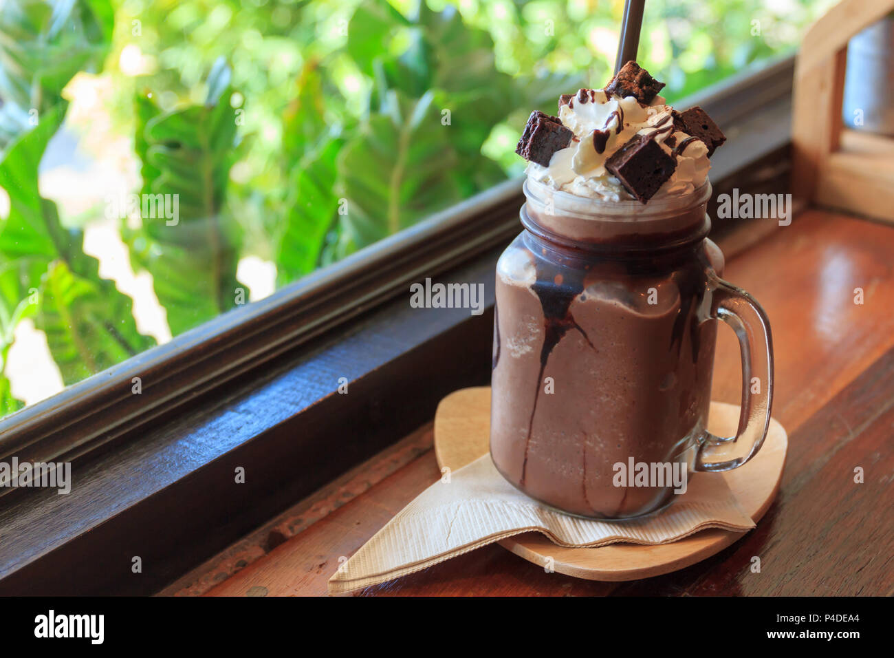 Lait frappé au chocolat avec crème fouettée brownie sur table en bois, fenêtre en arrière-plan, de boissons café de l'été. Banque D'Images