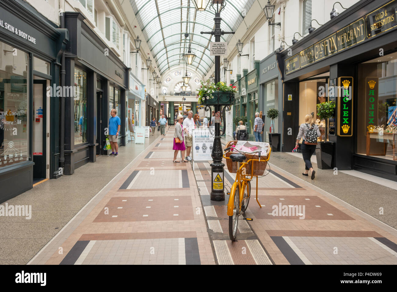 Les consommateurs et un vélo jaune à l'intérieur de l'Arcade, Bournemouth, Dorset, UK Banque D'Images