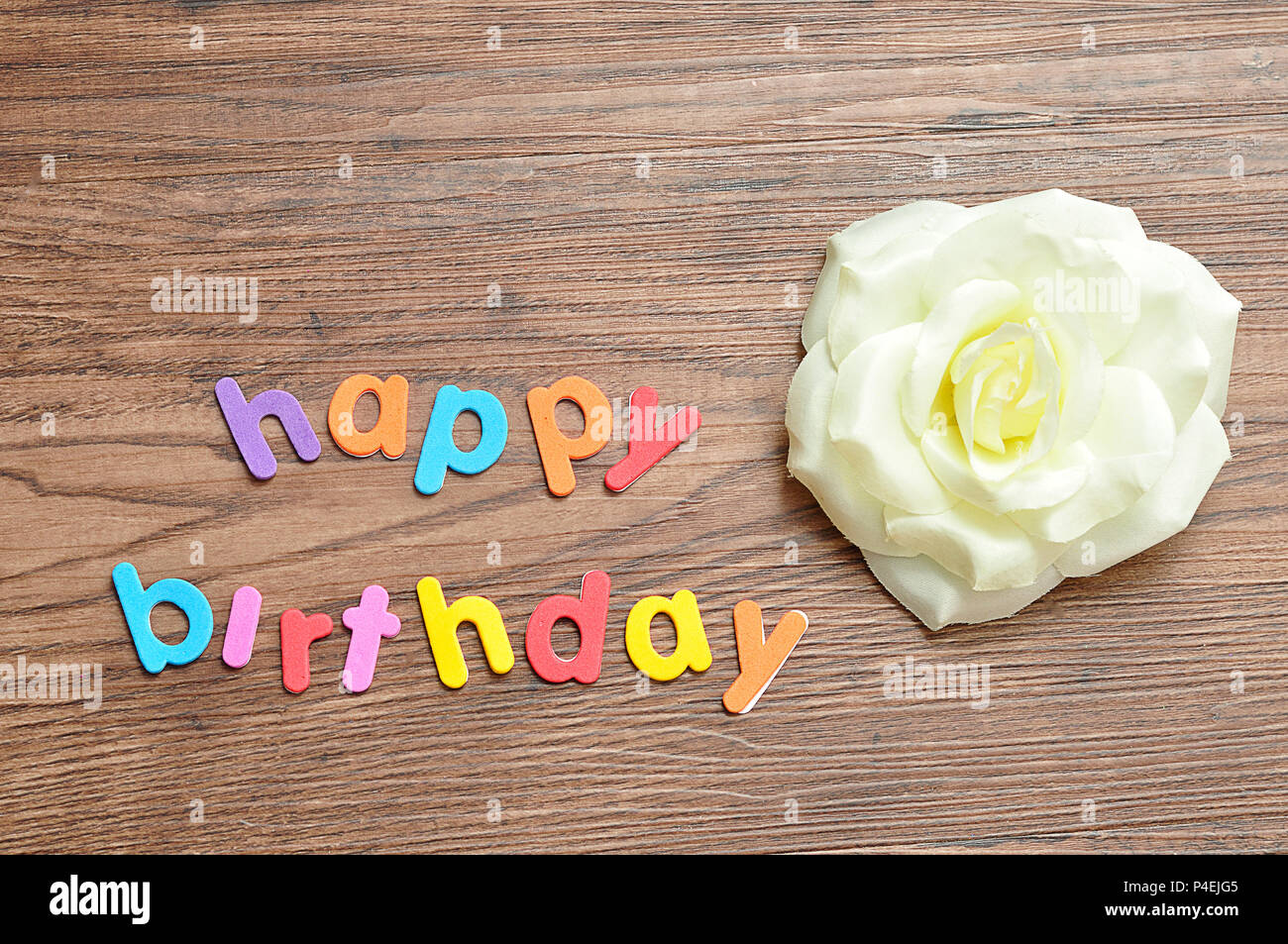 Joyeux Anniversaire En Lettres Colorees Affichees Avec Une Rose Blanche Photo Stock Alamy