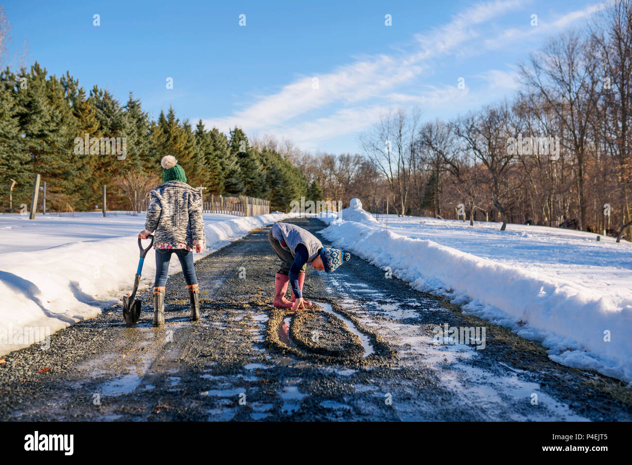 Garçon et fille jouant dans la route dans la neige fondante Banque D'Images