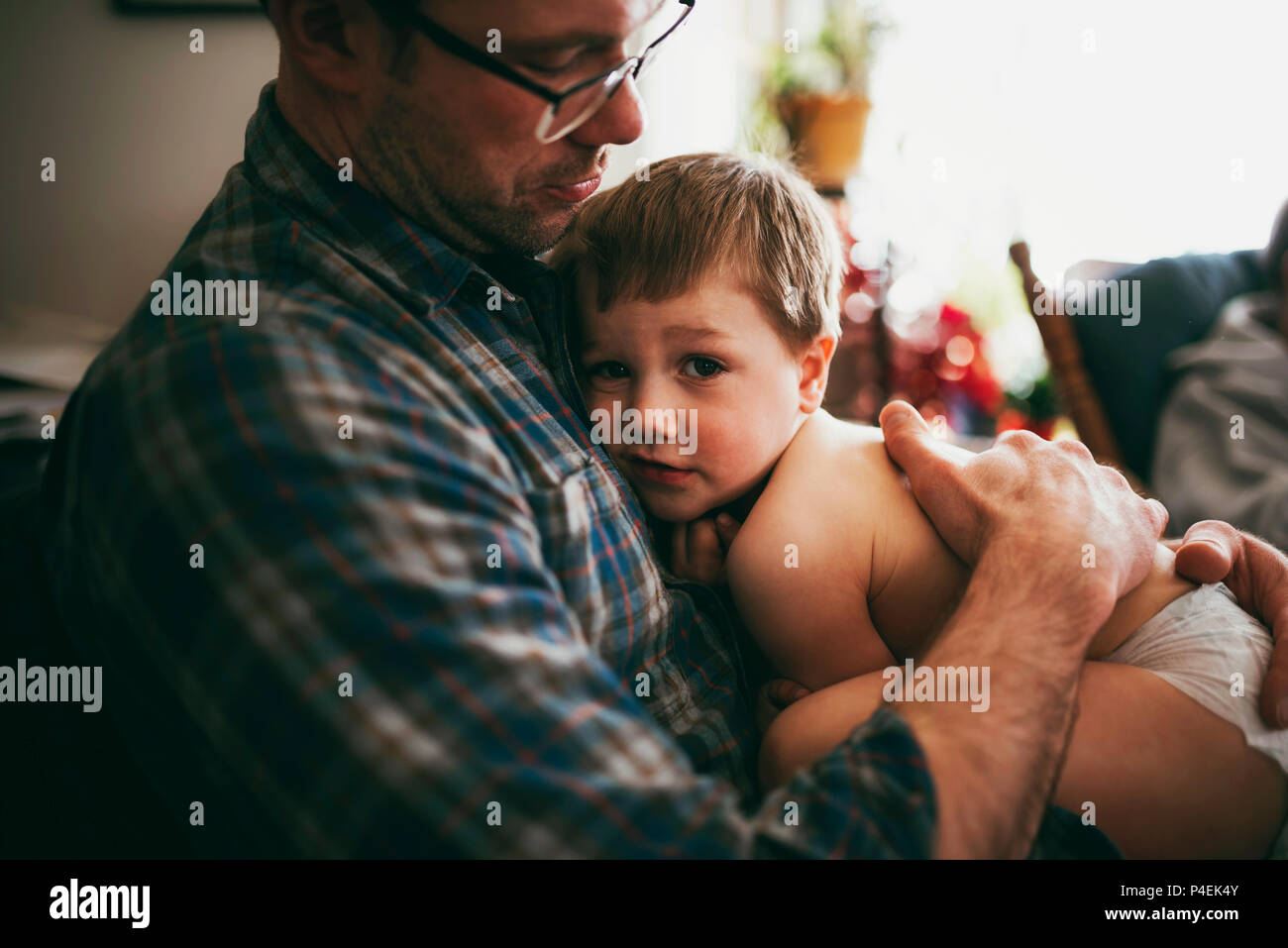 Père assis sur la table de câliner son fils et en l'embrassant sur la tête Banque D'Images