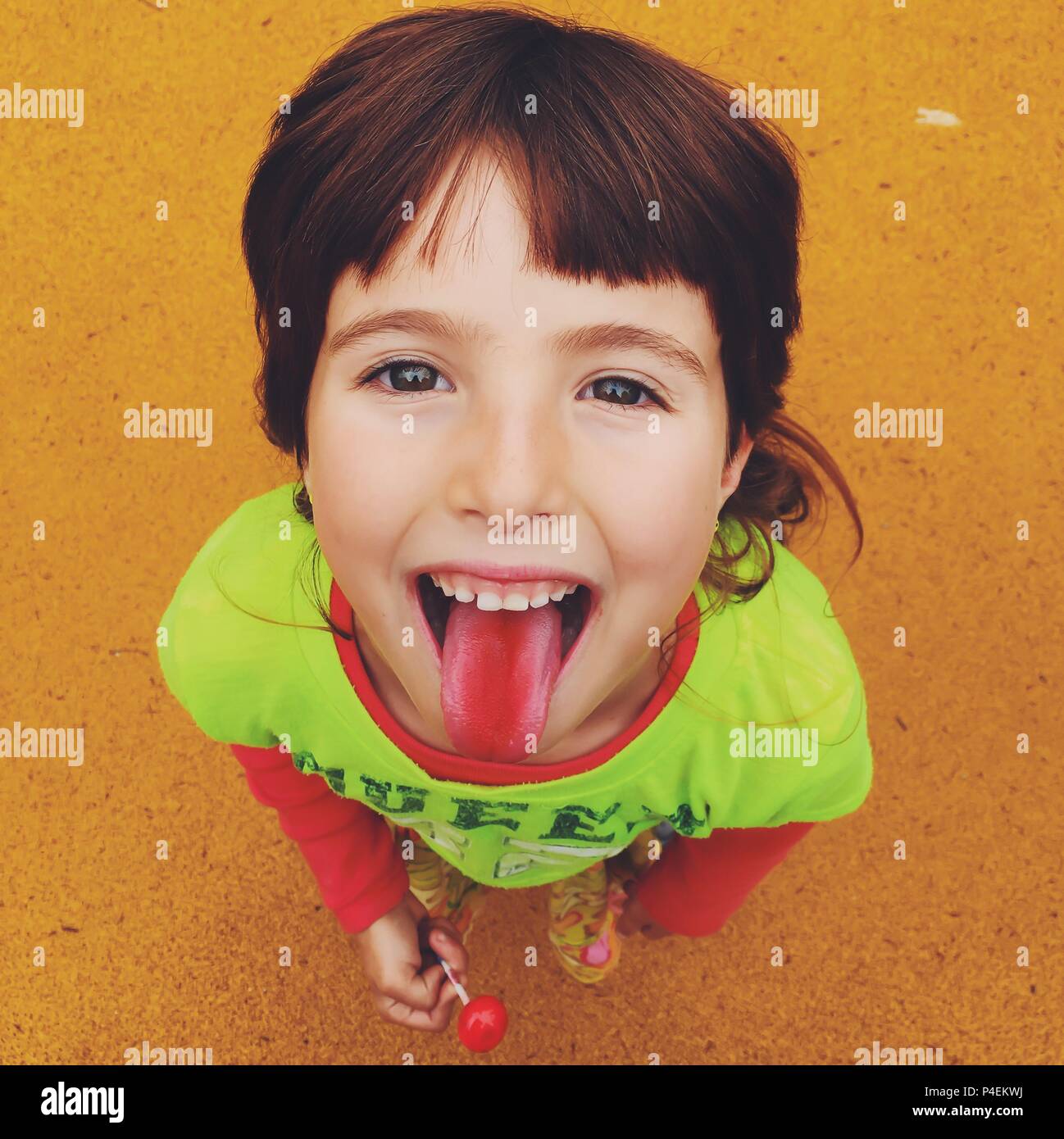 Portrait of a smiling girl eating a lollipop et collage hors de sa langue rouge Banque D'Images