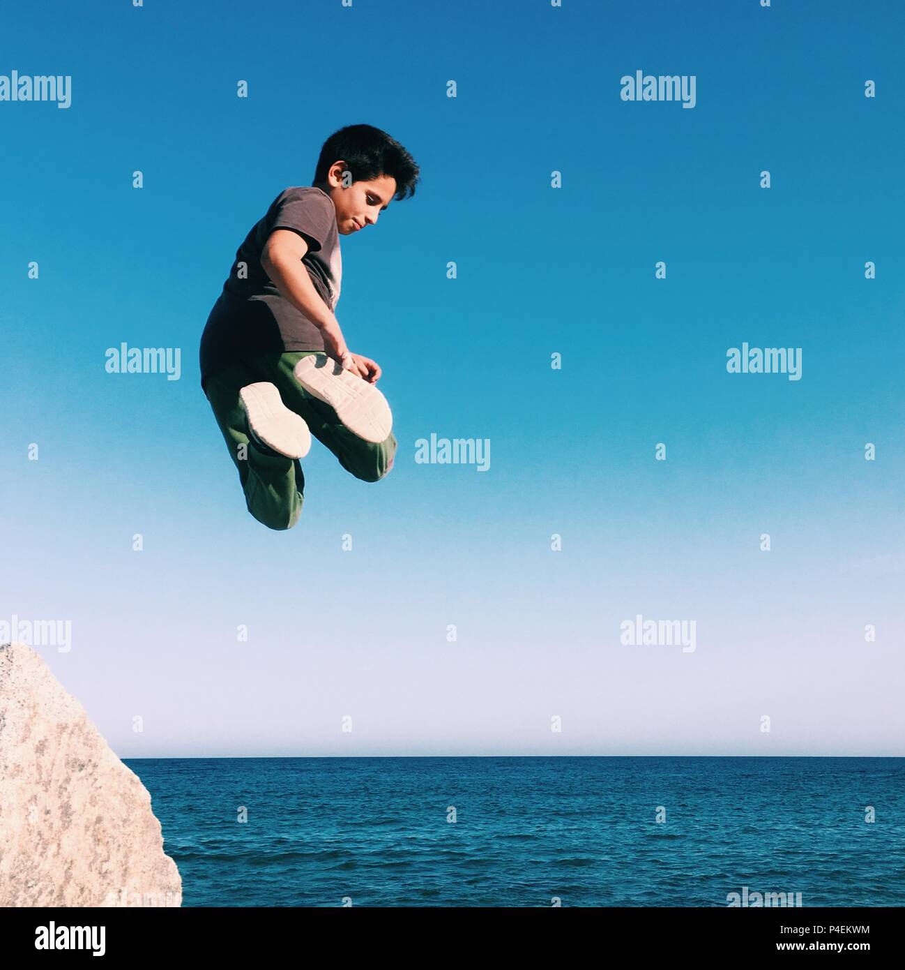 Garçon sautant en l'air sur la plage Banque D'Images